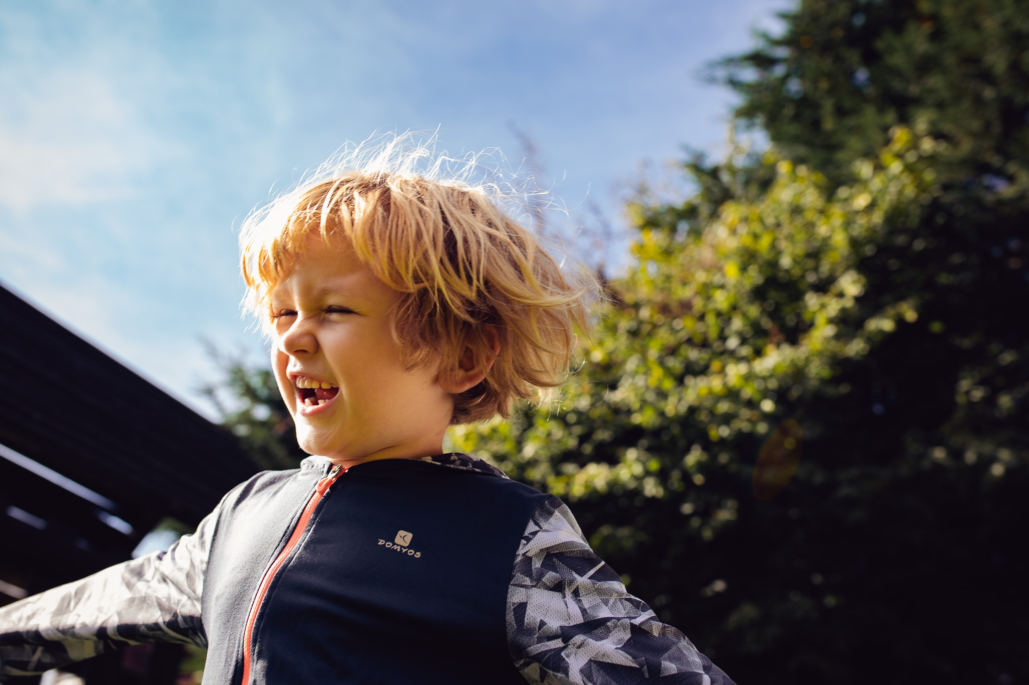 Kai in a garden laughing and smiling during a family photo session.