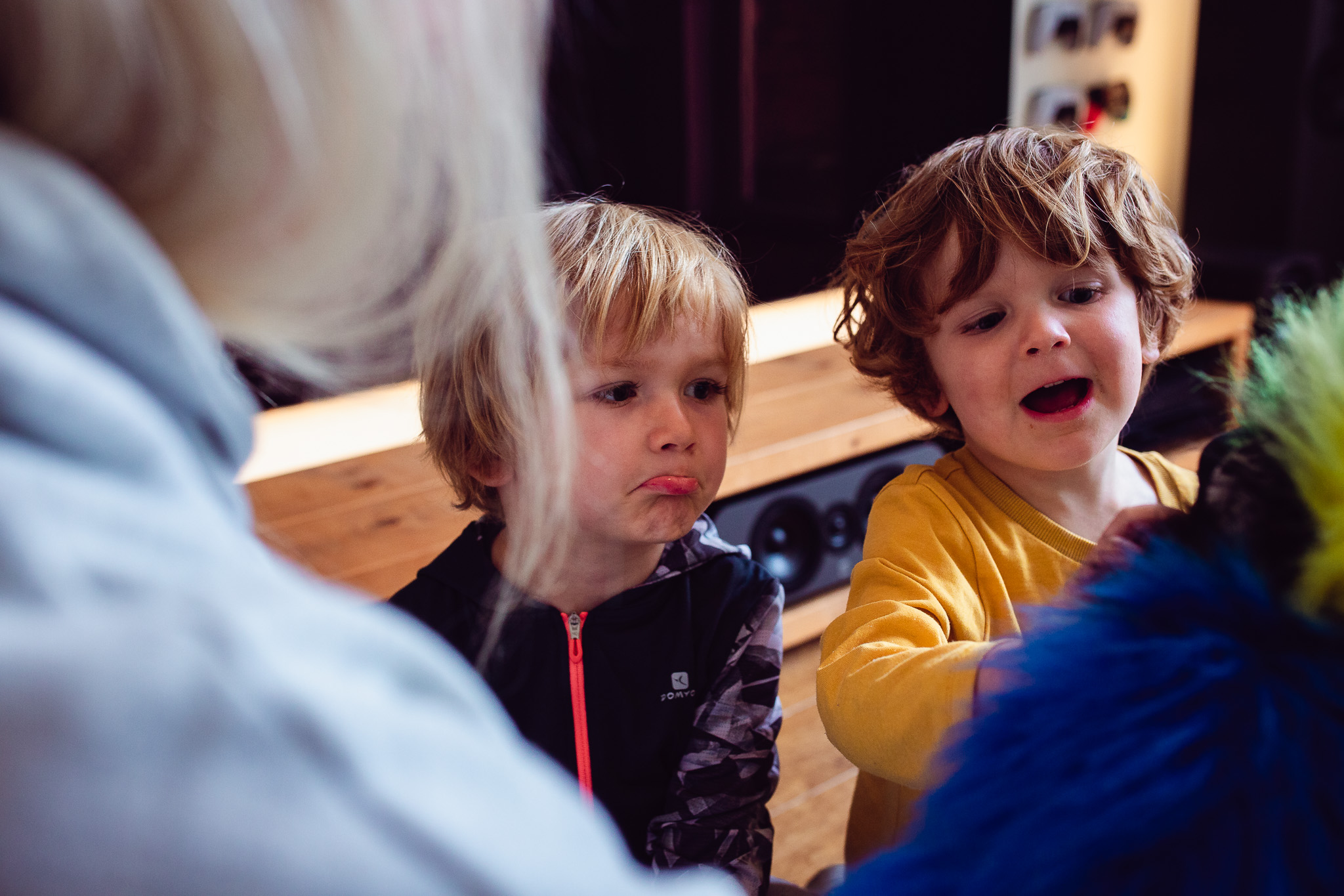 Kai and Leo playing with their mum who's holding a blue hand puppet during a family photo session.