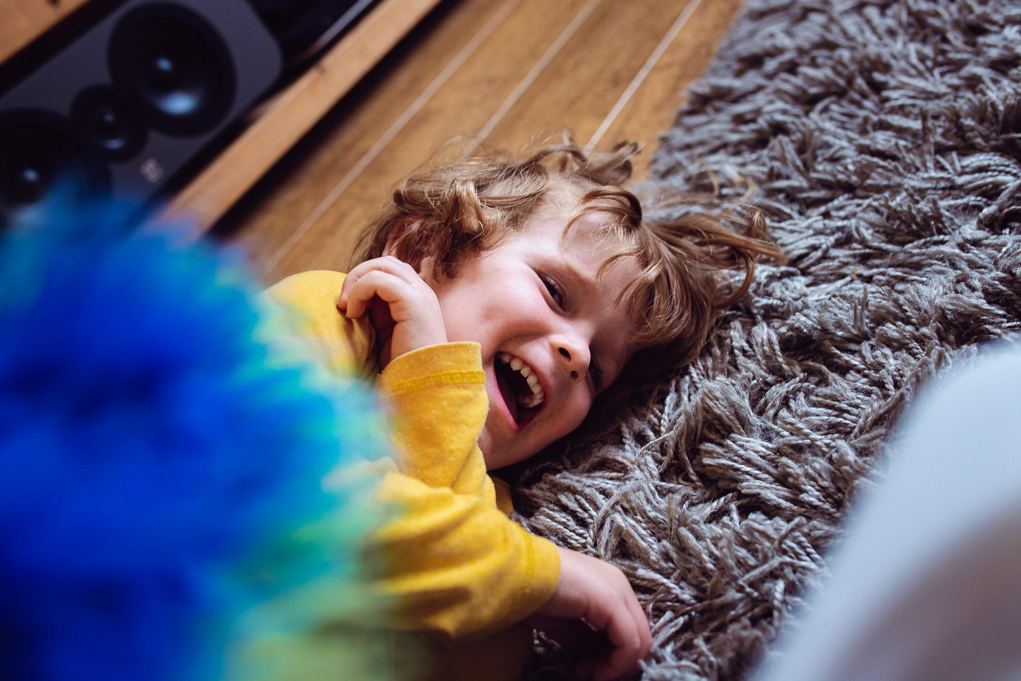 Leo laughing and lying down on a fluffy carpet during a family photo session