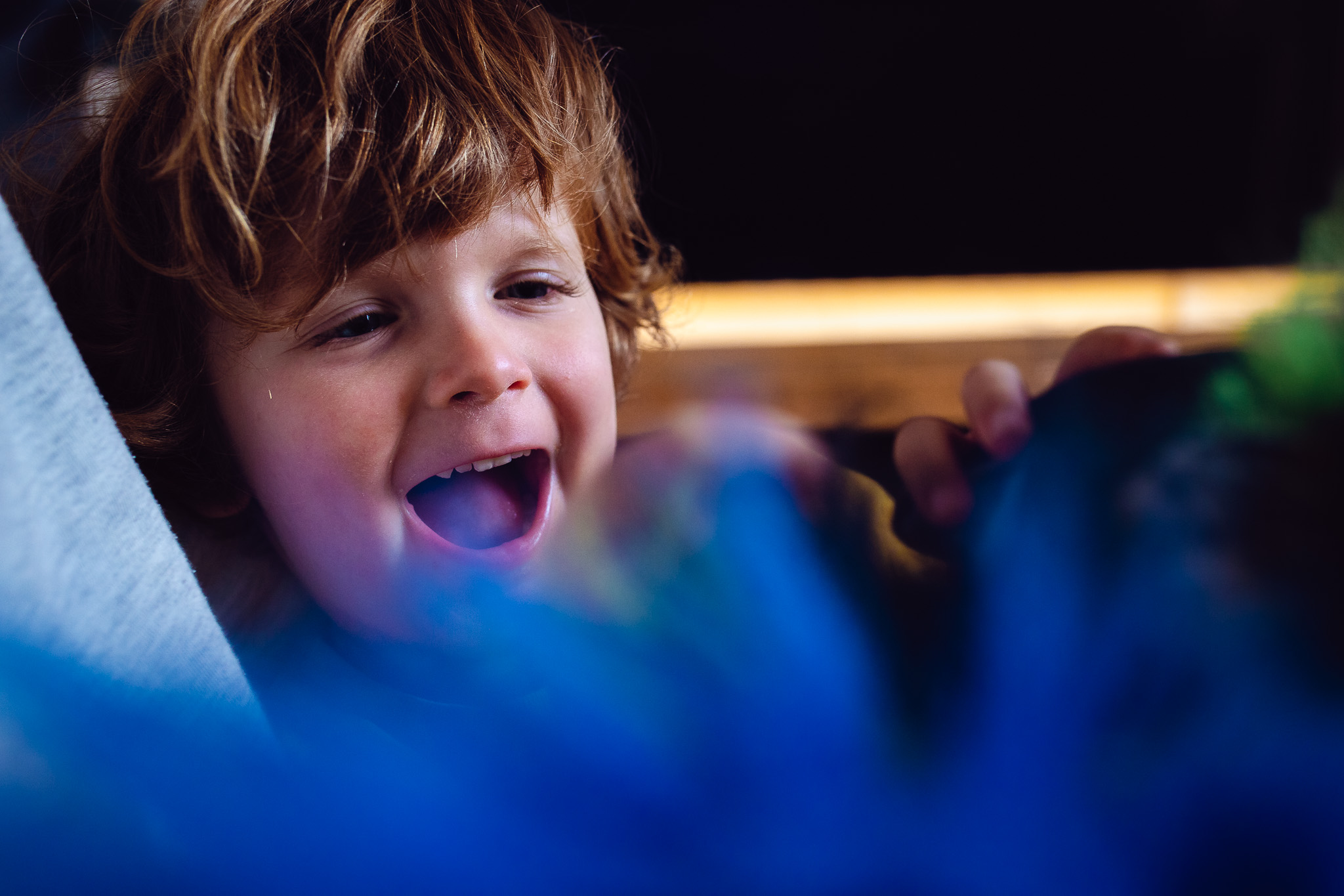 Leo laughing at a blue puppet during a family photo session.