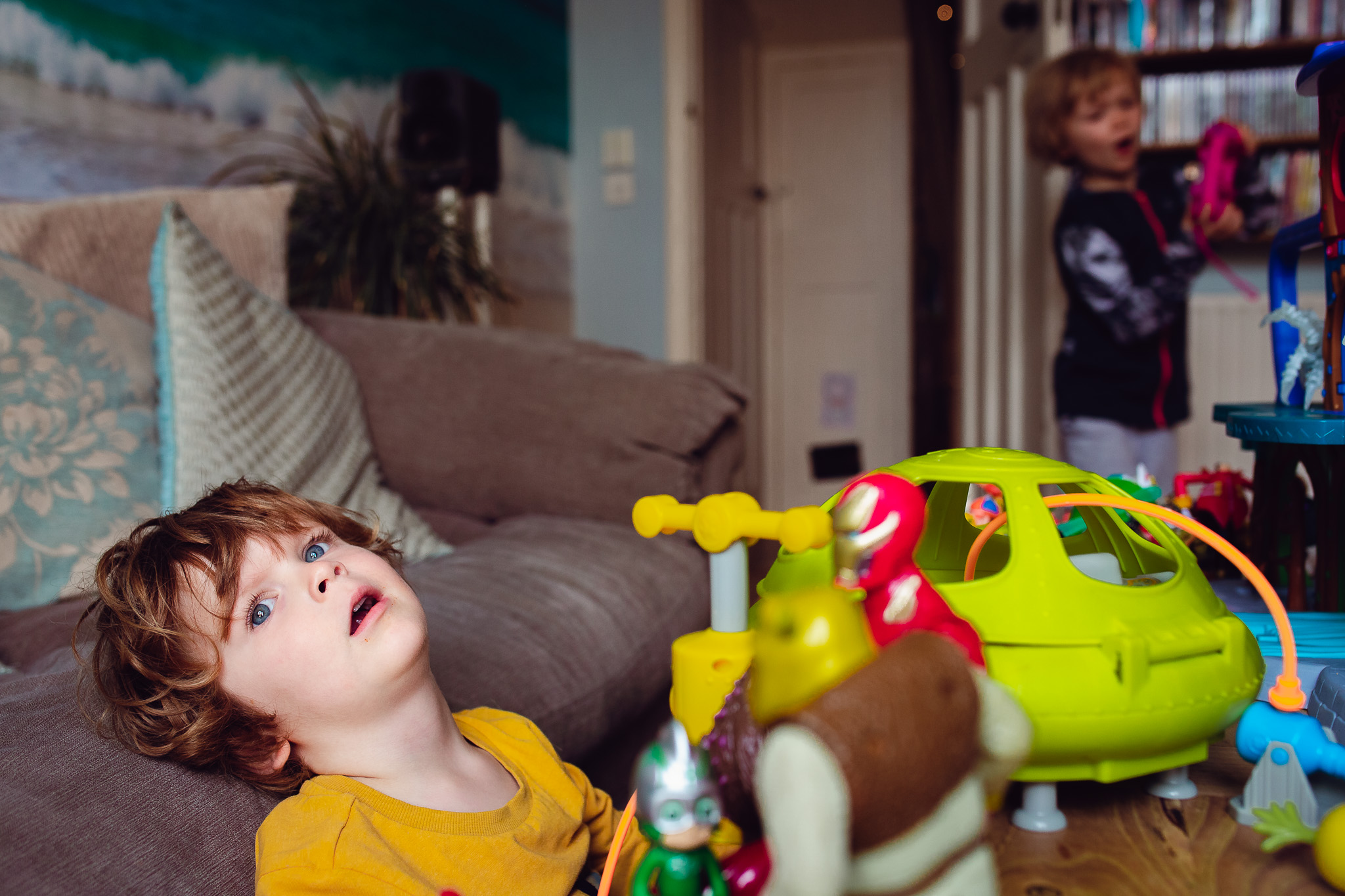 Leo and Kai playing together with their toys in their living room during a family photo session