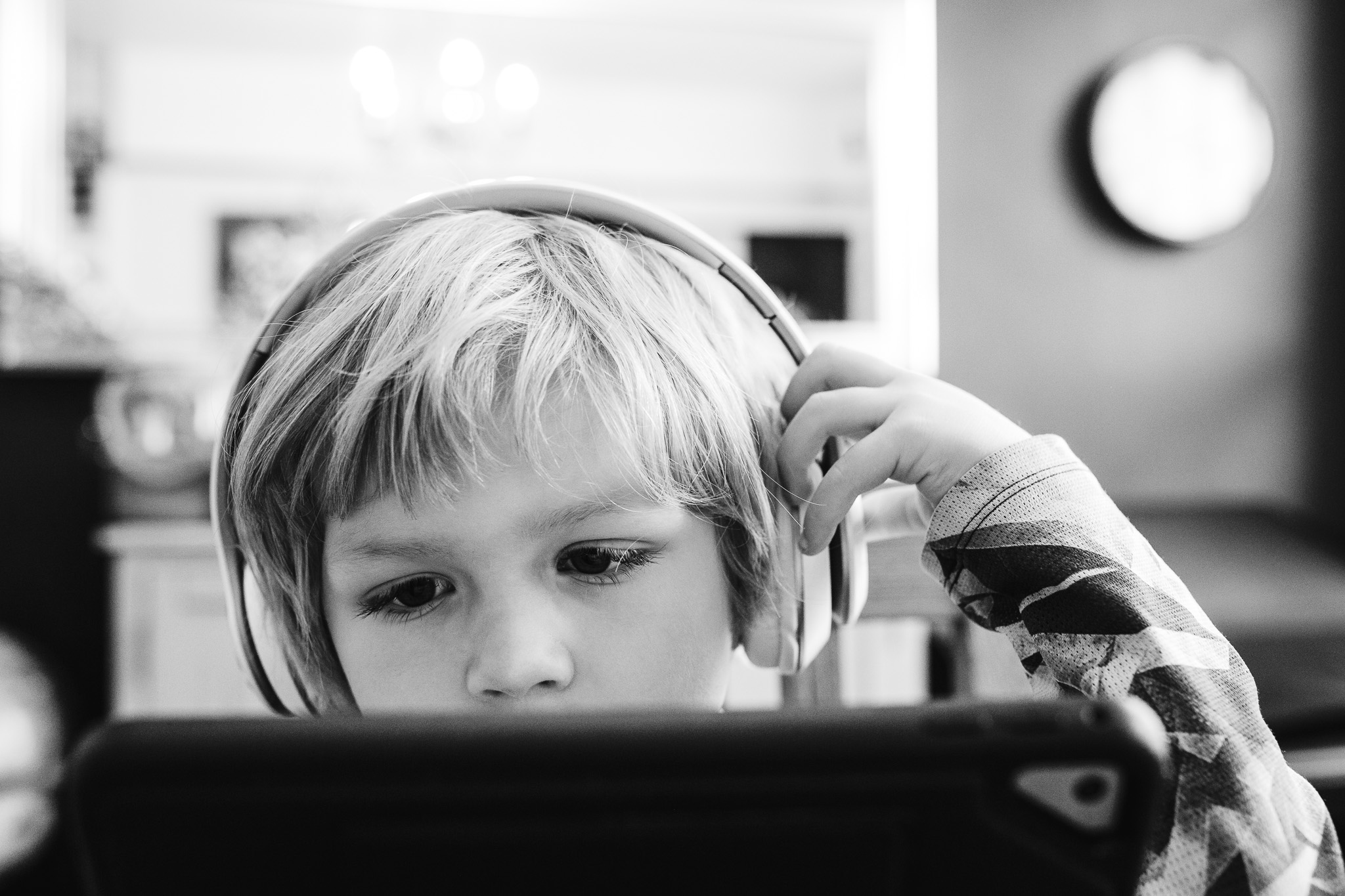 Kai wearing headphones looking at an iPad during a family photo session.