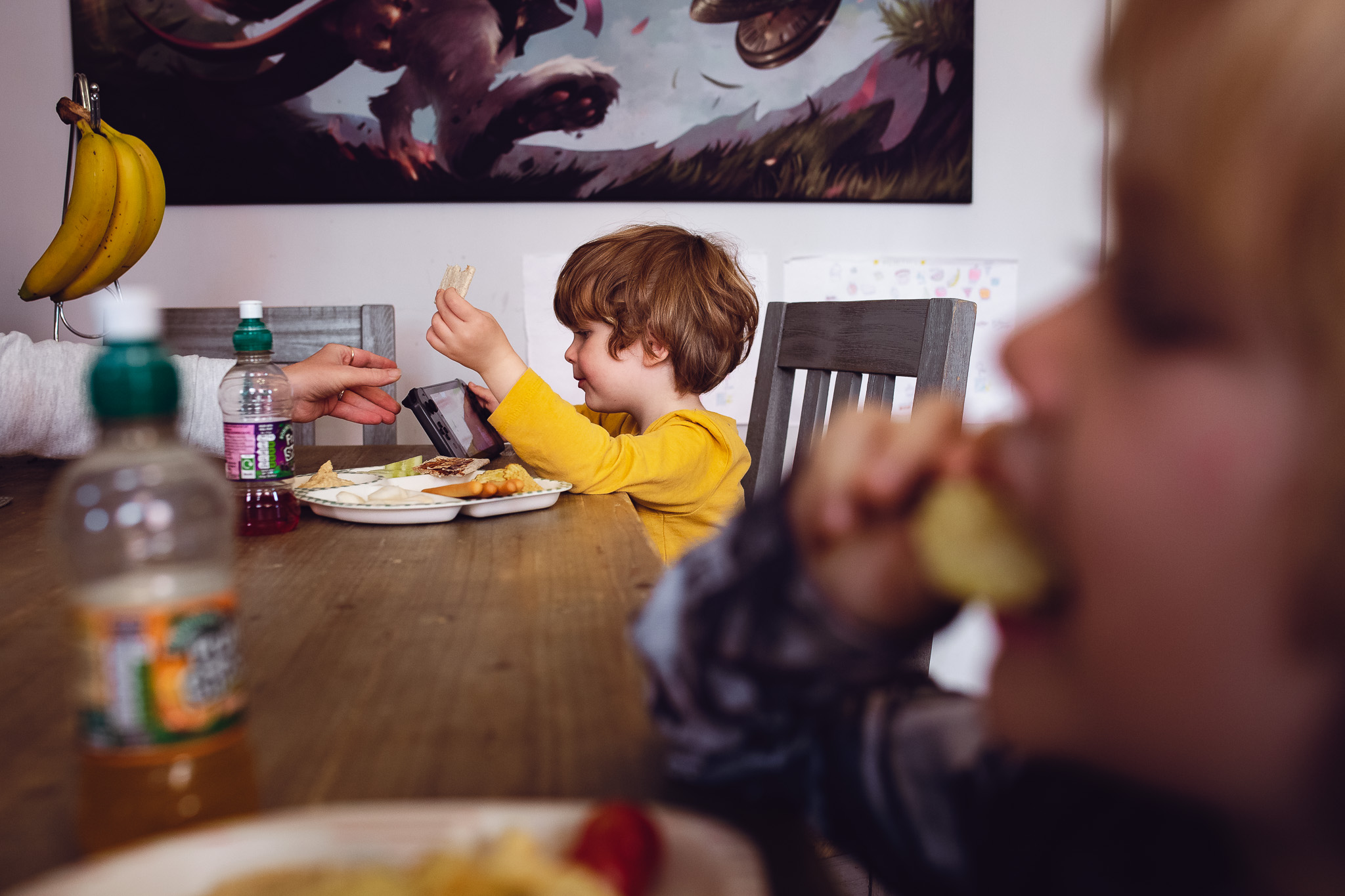 Leo eating lunch and playing on his Nintendo switch at the table during a family photo session