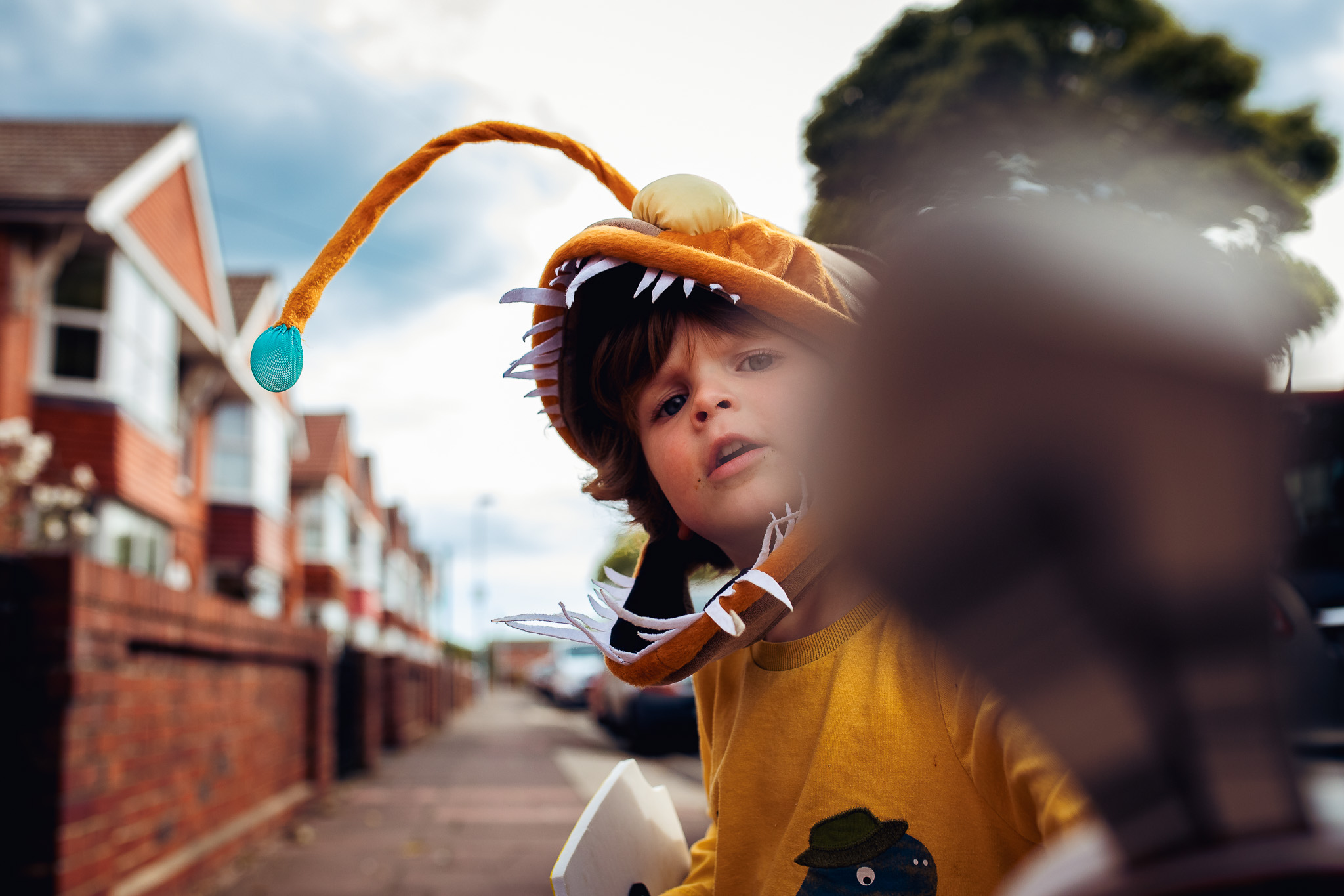 Leo wearing an angler fish hat holding a sword out to the camera during a family photo session.
