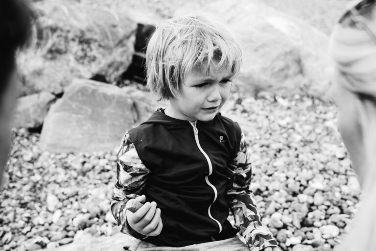 Kai crying on Brighton Beach after a fall during a family photo session.