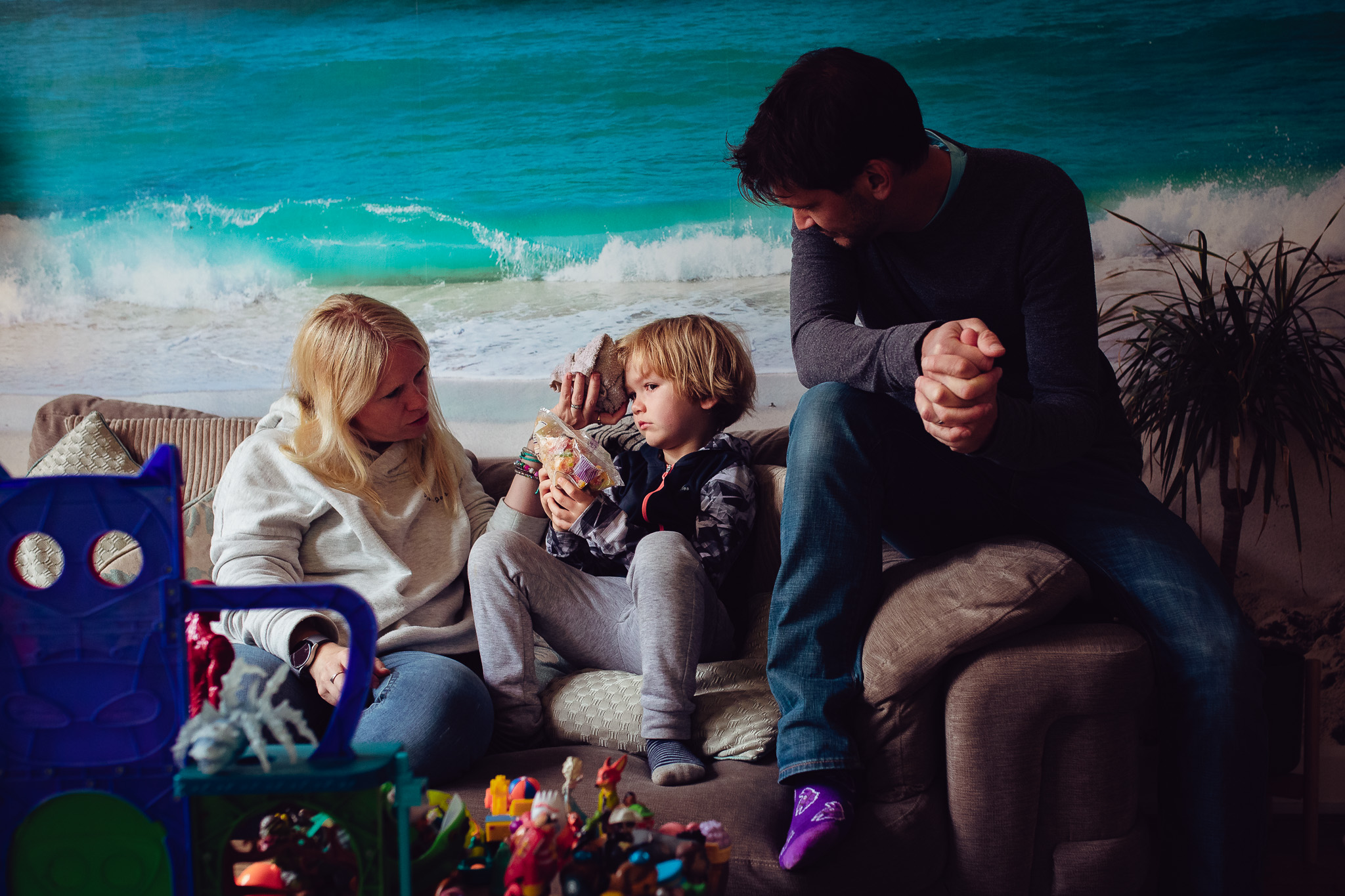 Mum and dad looking after their son after a fall and icing his head during a family photo session