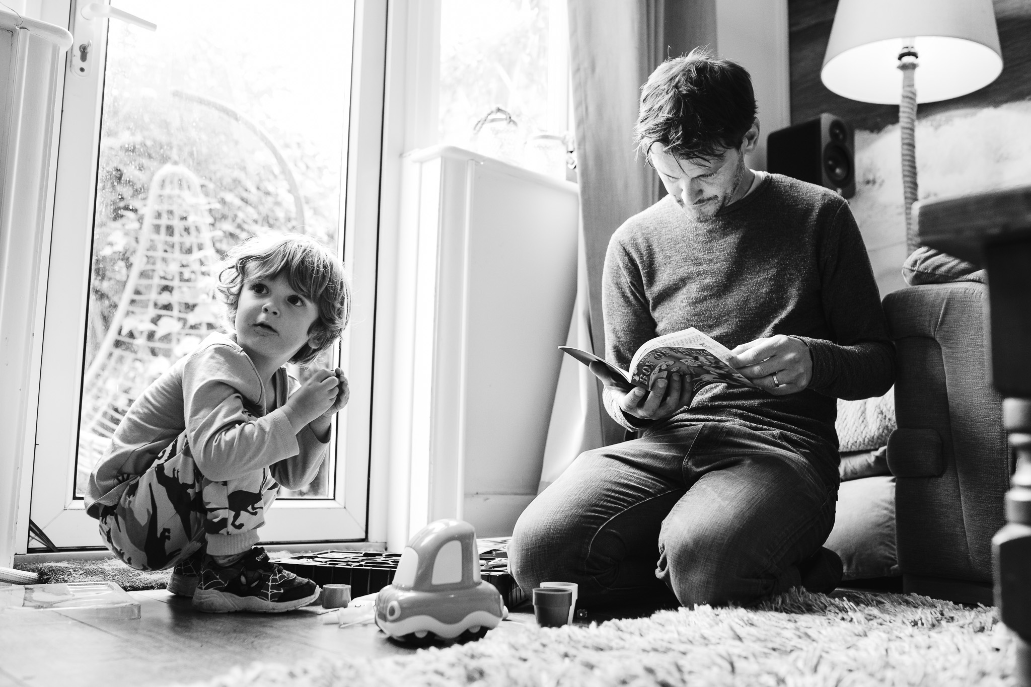 Young boy and dad sitting on the floor and reading rules of a game during a family photo session