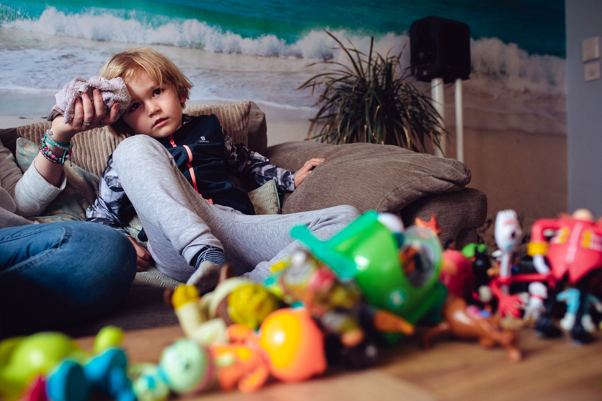 Kai sitting on the sofa with an iced flannel to his head during a family photo session.