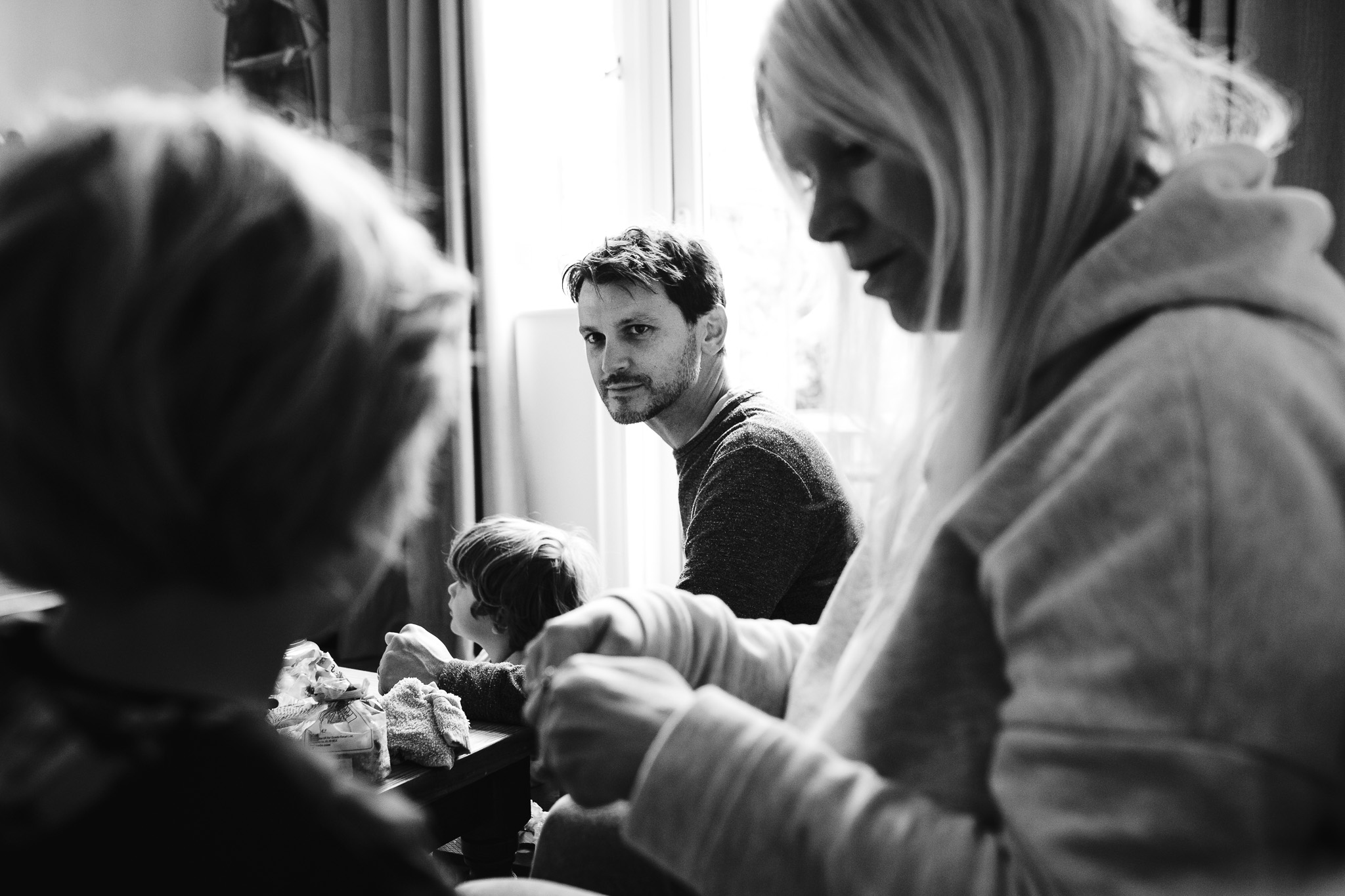 Dad sitting on the floor looking over at his son and wife during a family photo session.