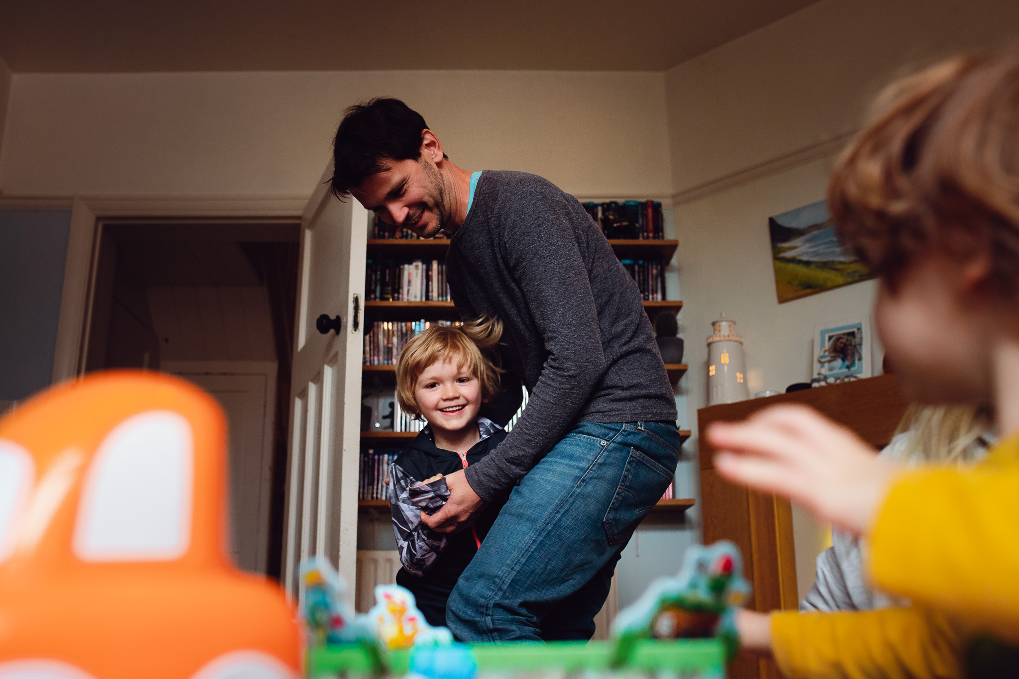 Dad and son laughing and playing together in their living room during a family photo session.