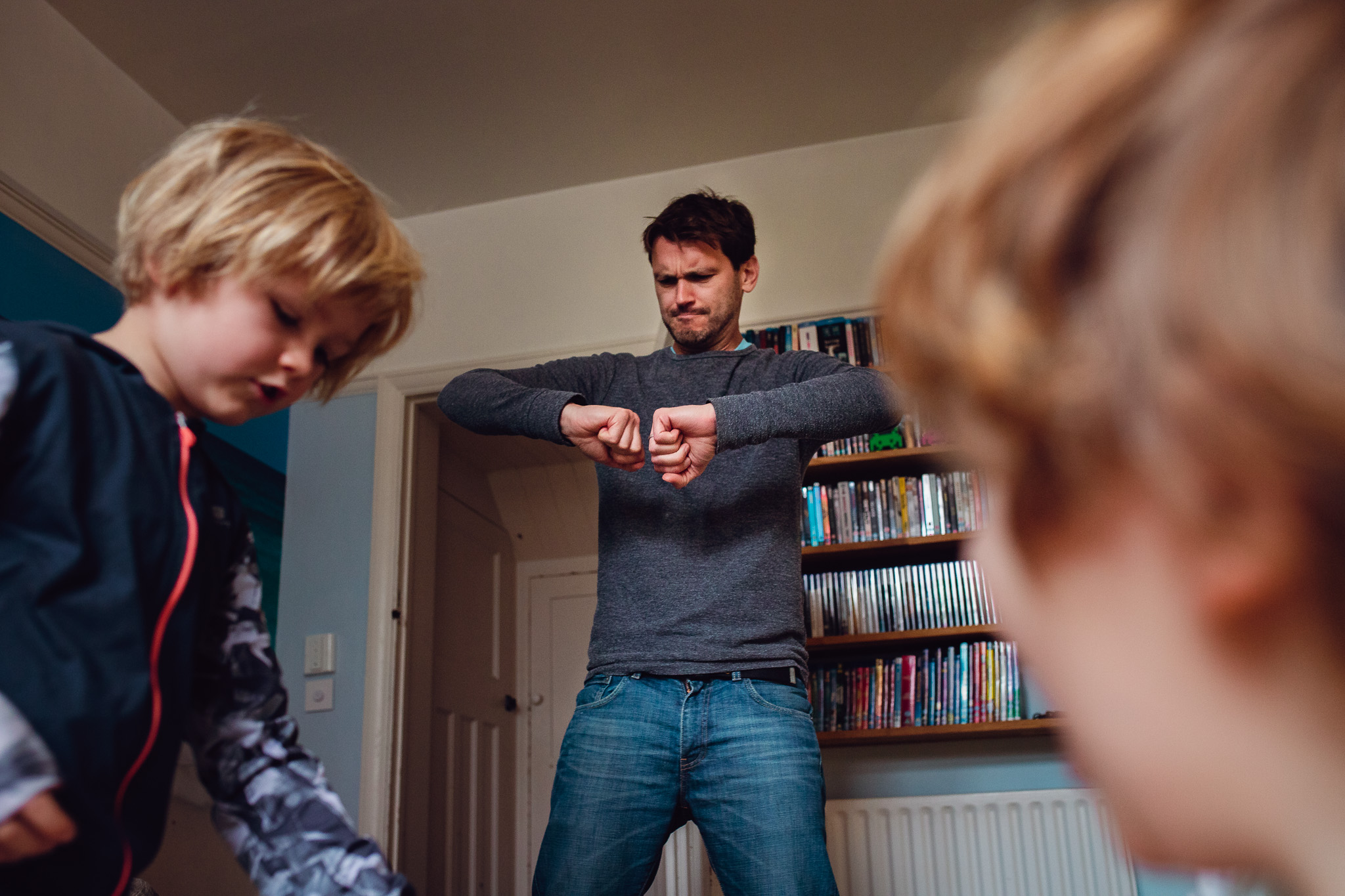 Dad acting out charades whilst his two sons watch during a family photo session.