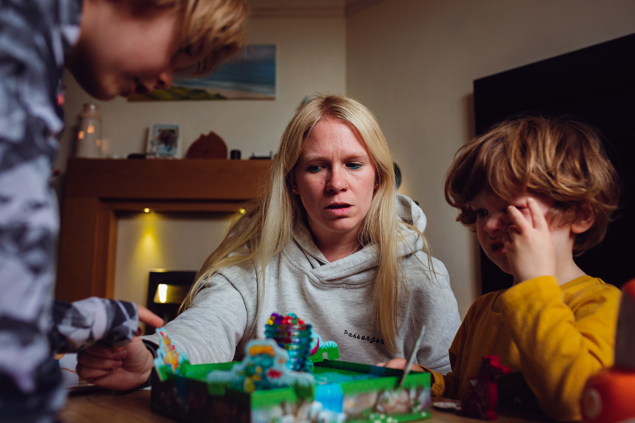 Mum and two young sons playing a board game during a family photo session.