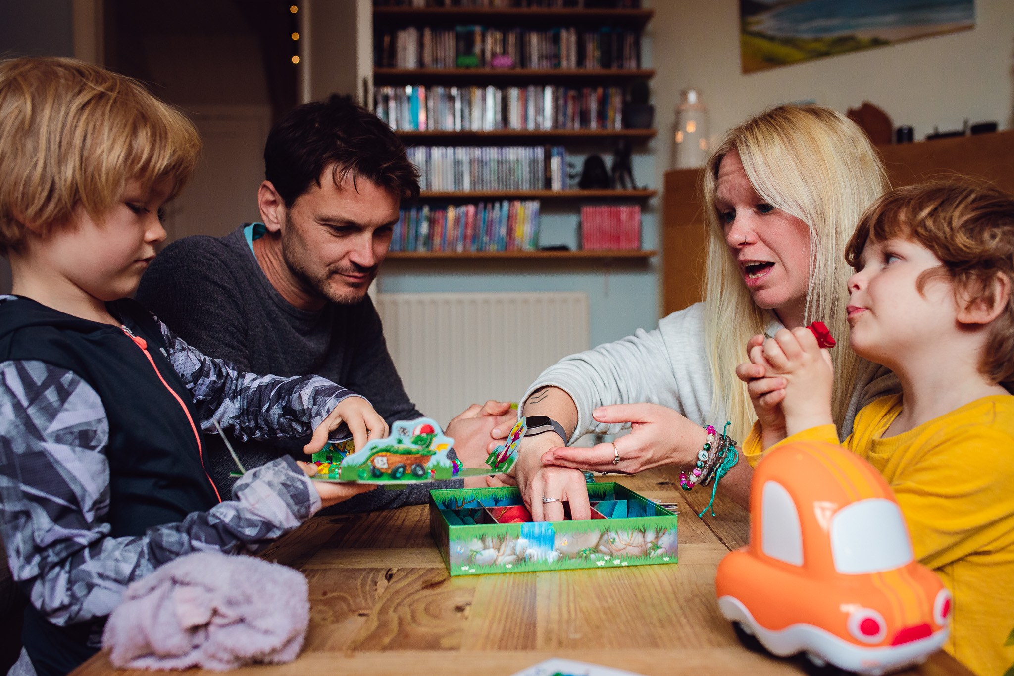 Leo and Kai play a board game in their living room with mum and dad during a family photo session.