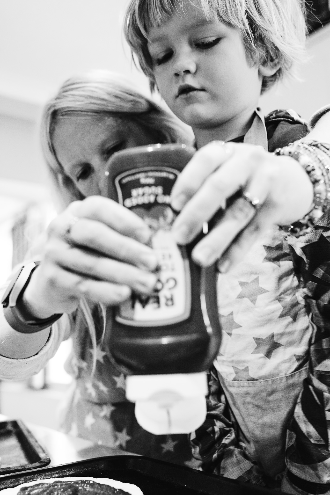 Mum and son squeezing ketchup bottle whilst cooking together during a family photo session.