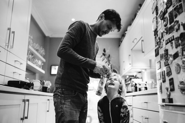 Dad is in kitchen with Kai opening a fruit popsicle during a family photo session.