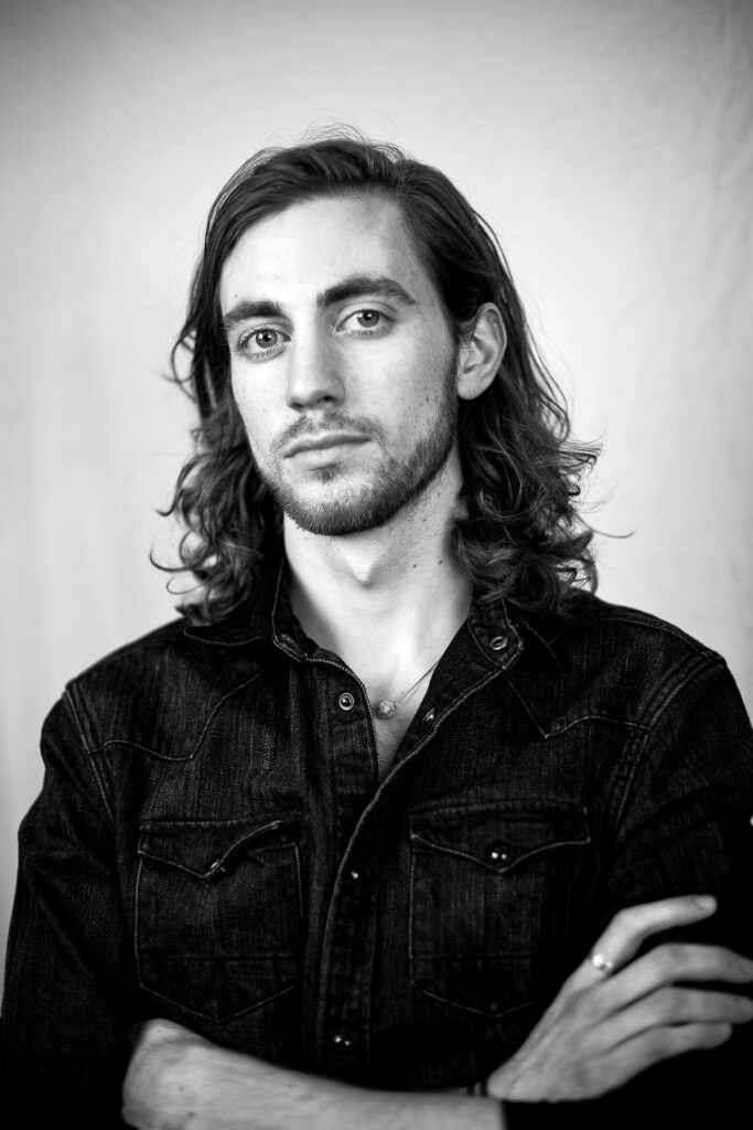 Indoor headshot at Rozewin Photography studio of a young man with arms crossed on simple background