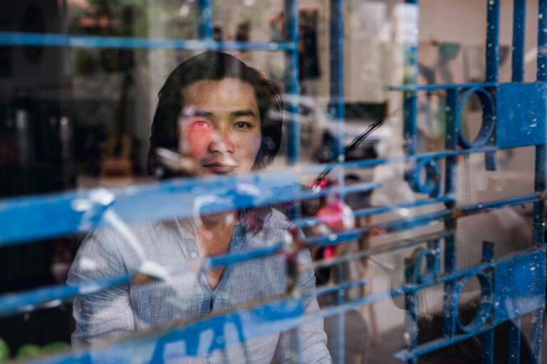 A young male poses for a portrait whilst looking through a window