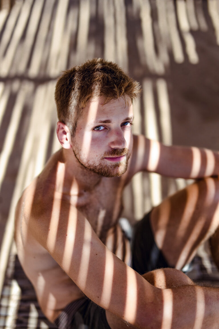 Mark poses for a portrait in a shady beach restaurant whilst waiting for his lunch