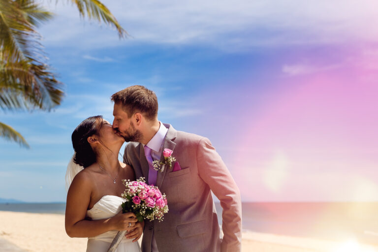 Bride and groom kissing on a white sandy beach at their Vietnamese destination wedding.
