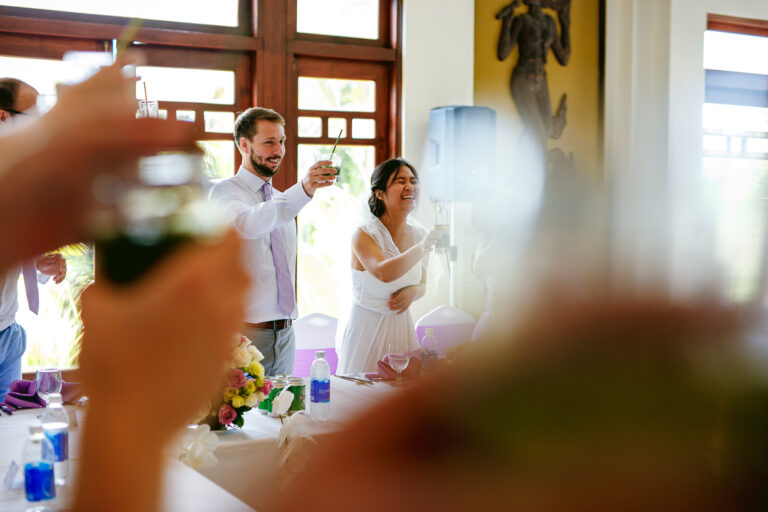 Bride and groom smiling while they make a toast at their wedding reception dinner.