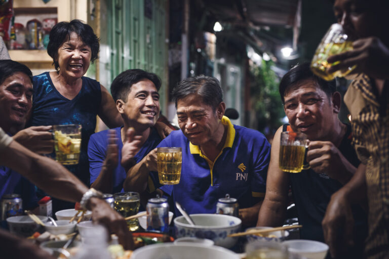 Vietnamese men and women sitting around laughing and drinking beer photographed for Word Magazine
