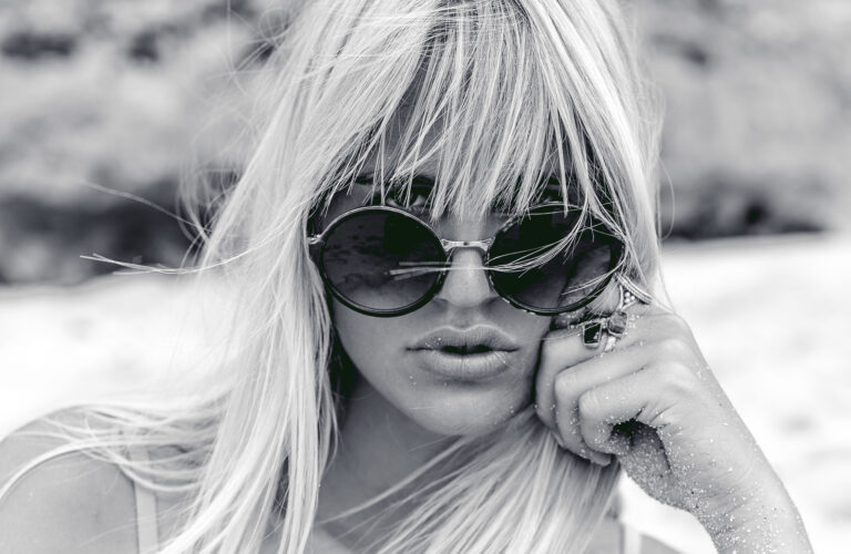 A young blonde woman rests her hand on her face during a fashion portrait session