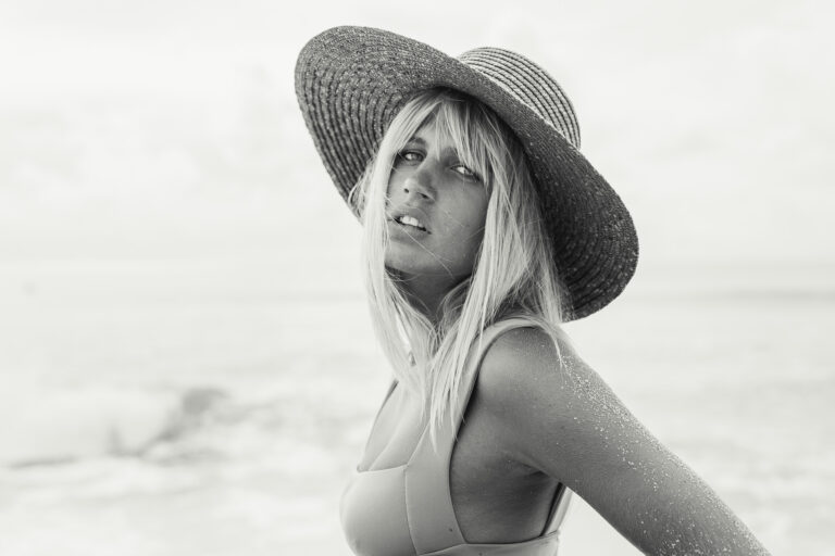 a young woman wearing a straw hat and Thaikila bikini top poses during an editorial session