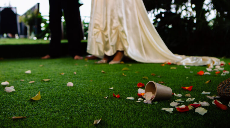 Cup on the floor with confetti spilling out onto the grass at wedding ceremony.