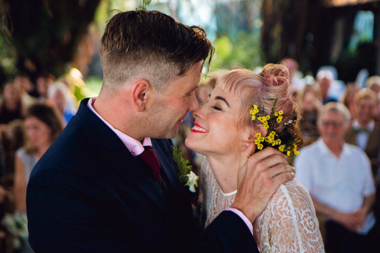 Bride and groom smiling and about to kiss at a wedding ceremony.