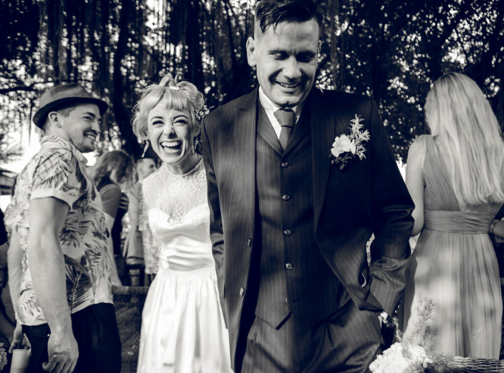 Bride and groom laughing whilst walking down the aisle after their destination wedding ceremony in Vietnam.