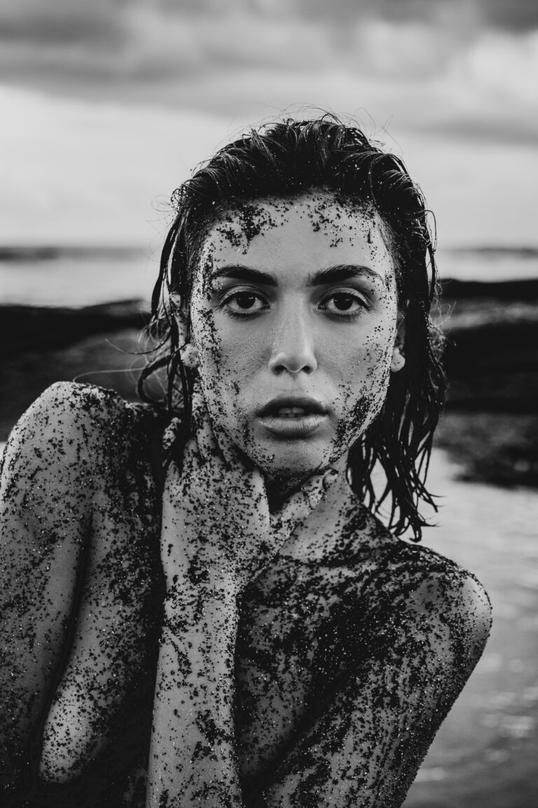 A young woman poses for a fashion portrait on the beach in Bali covered in black sand