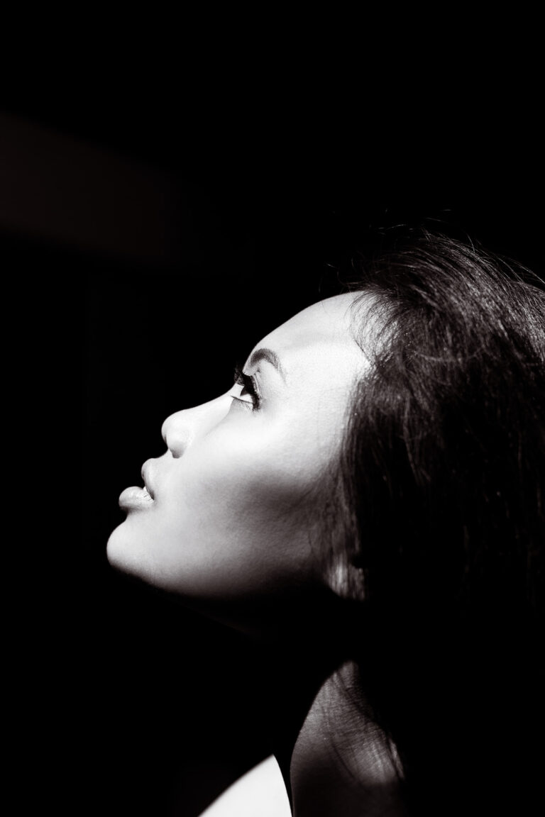 A beautiful young Indonesian woman poses for a portrait on a dark background