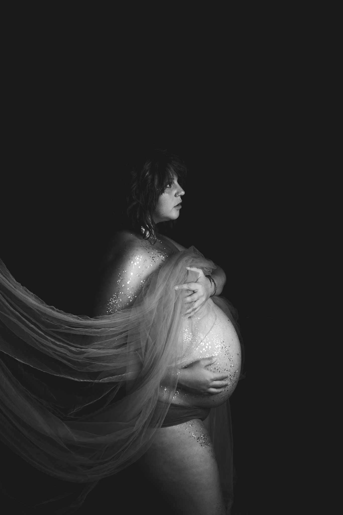 pregnancy portrait of heavily pregnant nude woman covered in glitter and tulle