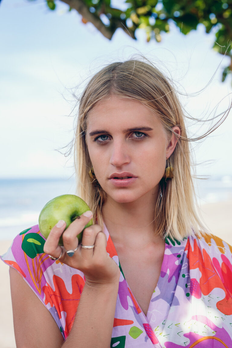 a young blonde woman holds up a green apple whilst posing for a portrait for State of Georgia