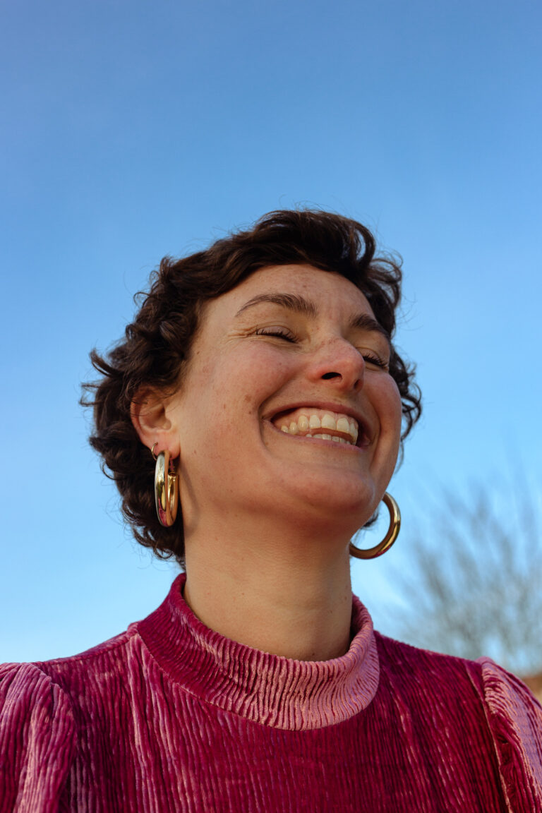 An outdoor headshot of a young smiling woman photographed by Rozewin Photography