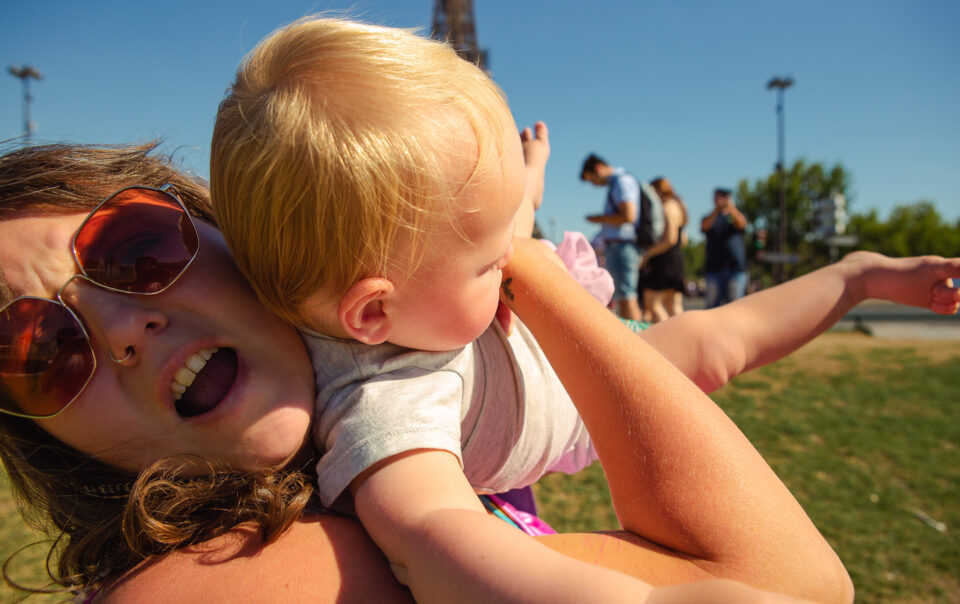 portrait of mum struggling with wriggling baby who's flinging himself into the air