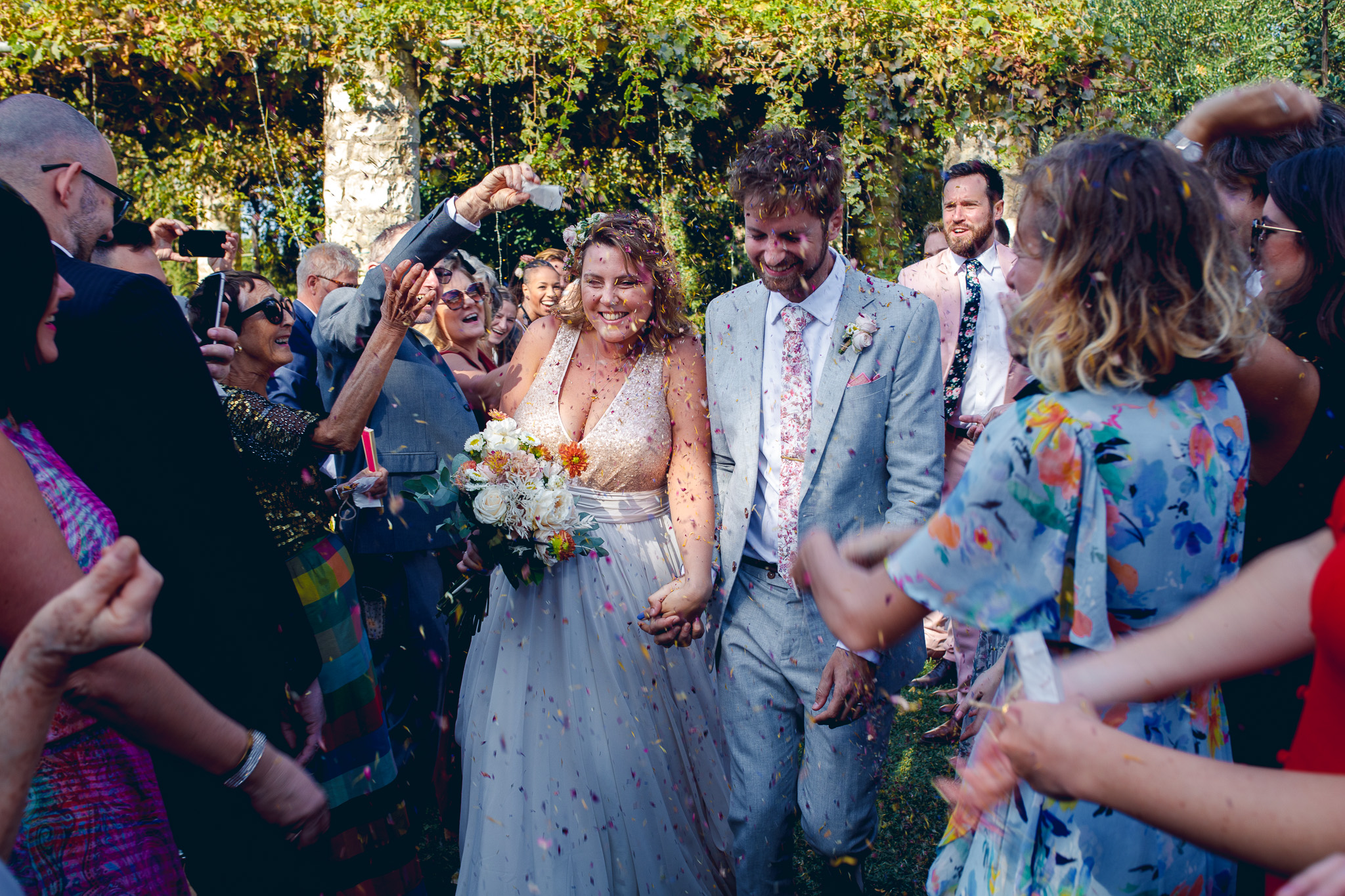 married couple walking through guests who are throwing biodegradable confetti