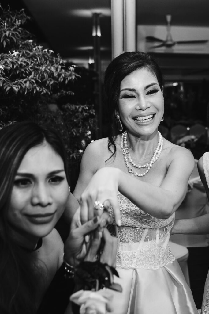 Bride smiles and shows her ring to her friend at the wedding reception.