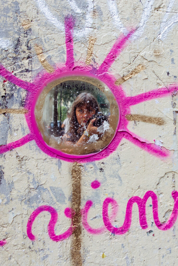 graffiti with a mirror on the wall with the reflection of a female photographer taking a photo
