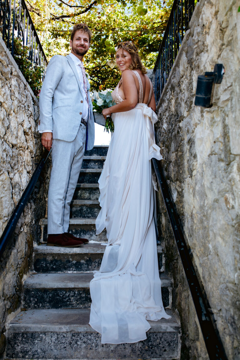 married couple standing on stairs at their wedding looking back over their shoulders