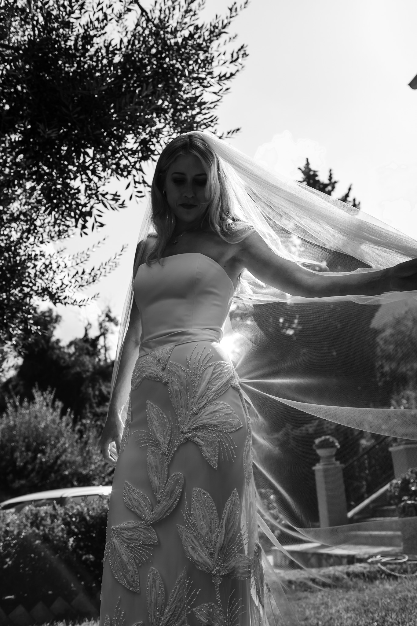 Alice lifts her veil to the side as she poses for a portrait in her wedding dress.