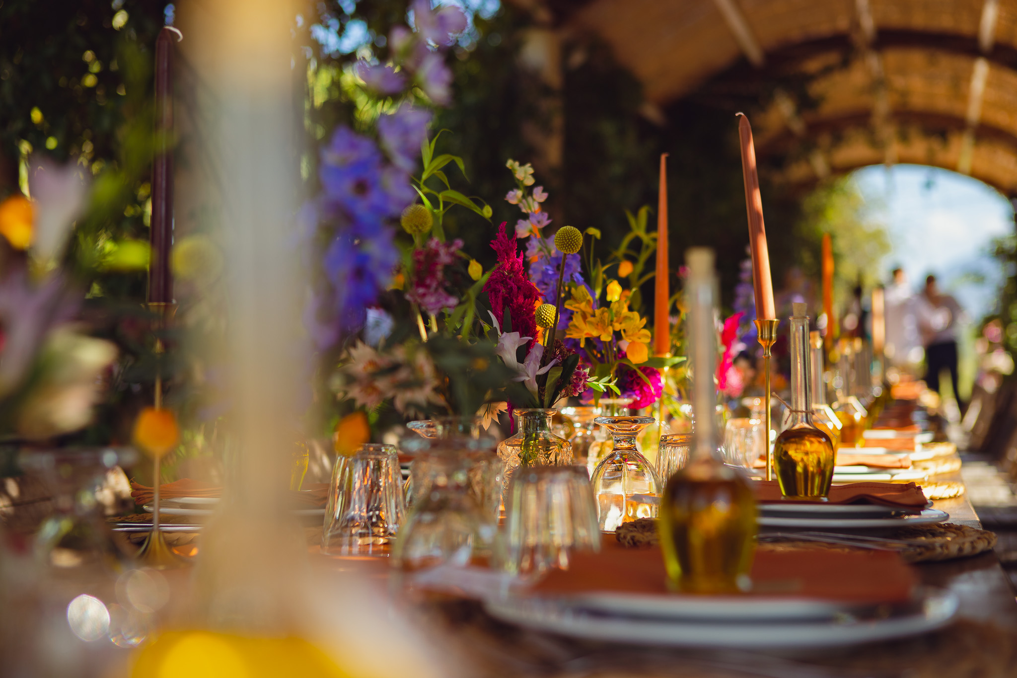A beautiful wedding dinner place setting with bright flowers and small olive oil bottles at Ambelonas, Corfu