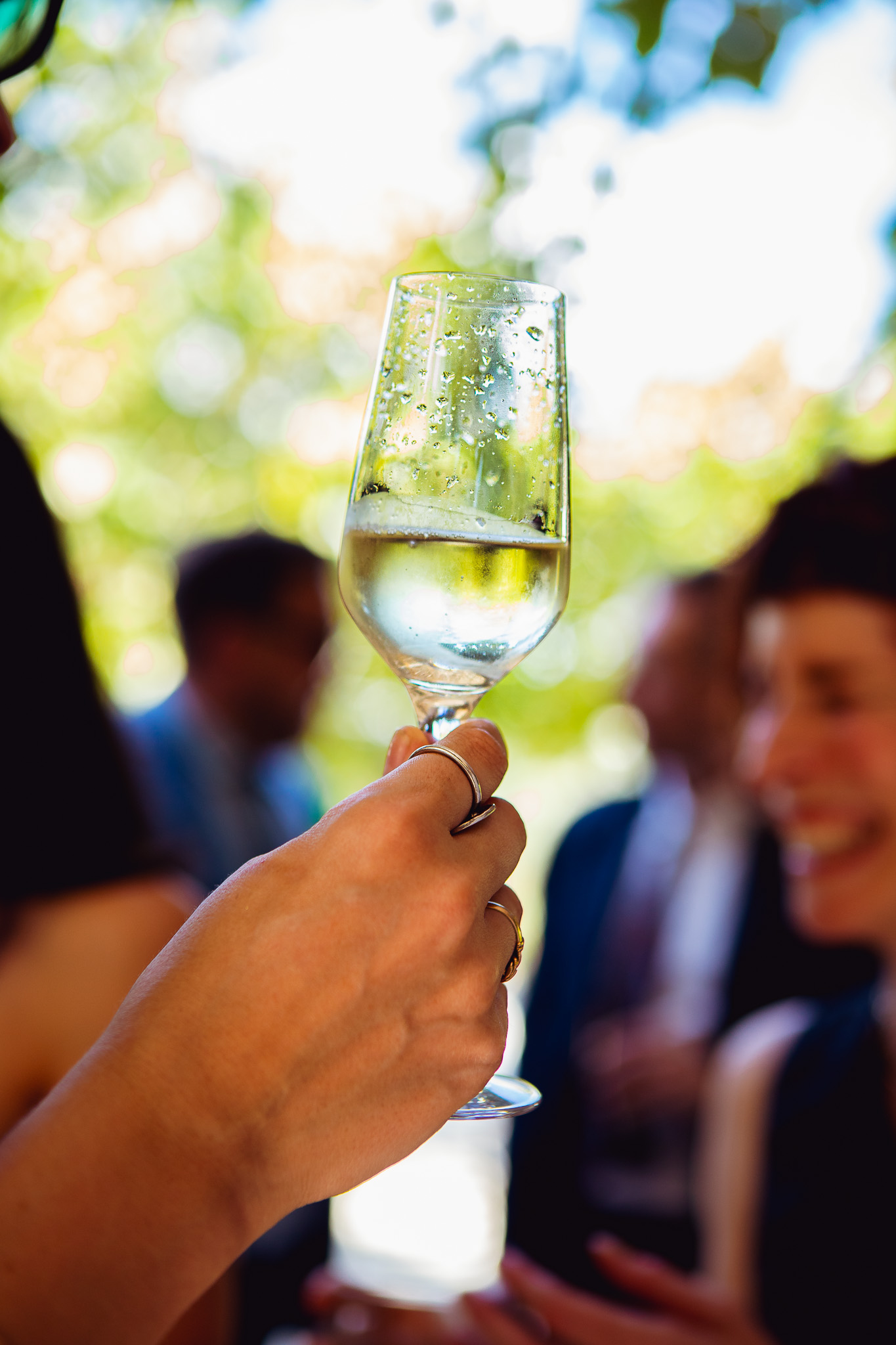 Woman's hand holding a full champagne flute at a wedding reception