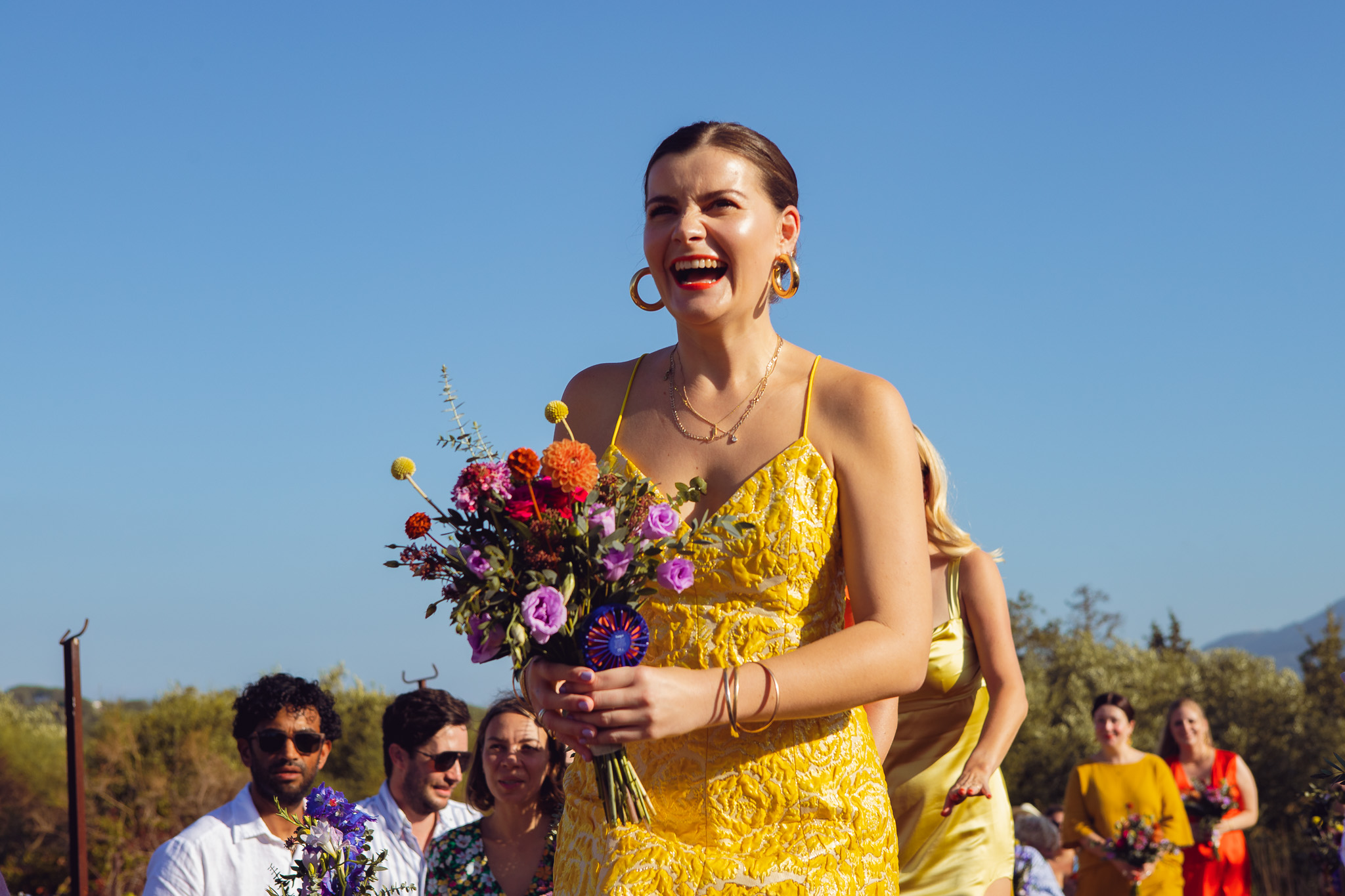 Bridesmaid laughs and walks down the aisle at the wedding ceremony in Ambelonas Vineyard, Corfu