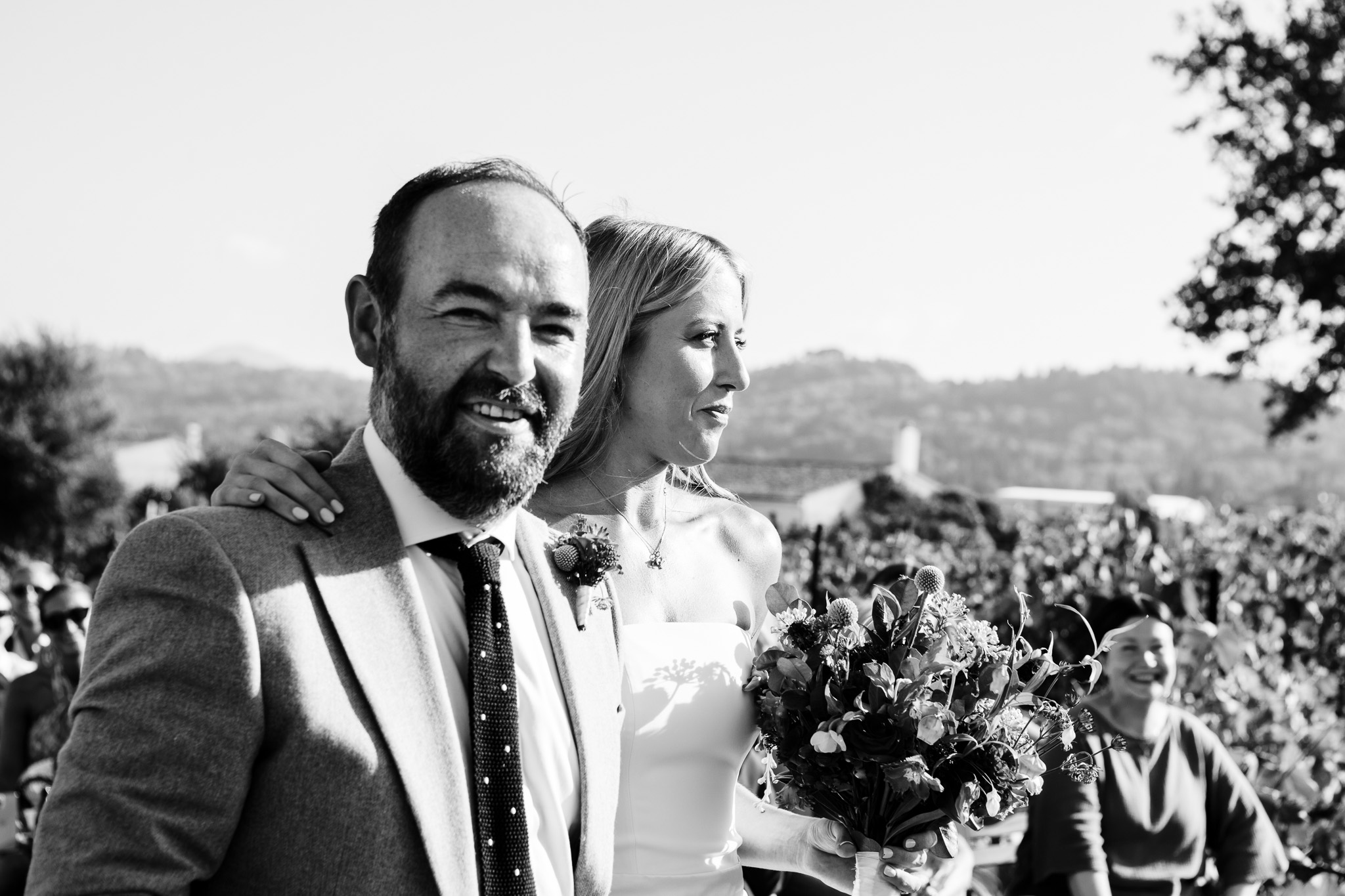 The bride holds the grooms shoulder as they smile at their wedding ceremony