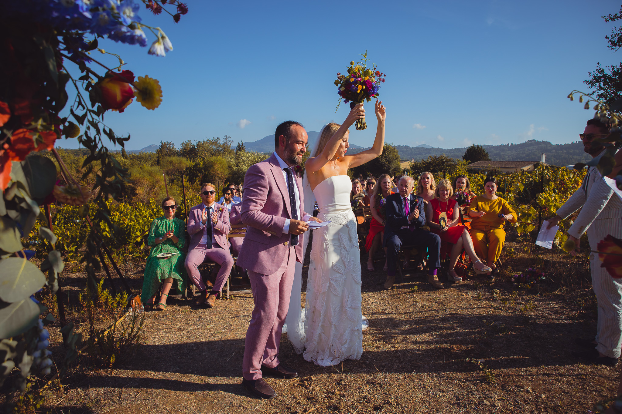 The bride throws her hands and bouquet up into the air as she stands next to the groom at a wedding recption