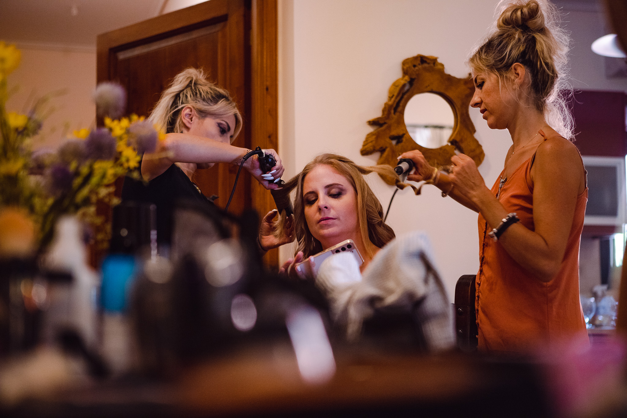 Bridesmaid is getting her hair done by two stylists in preparation for Alice and Tom's wedding.