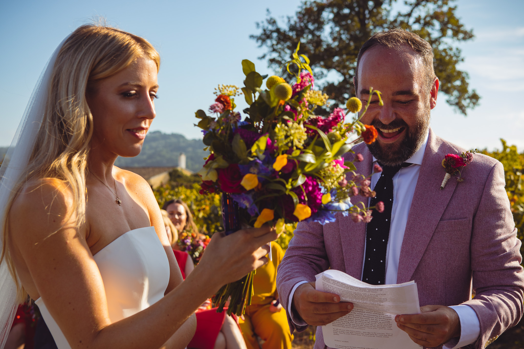 The groom reads of his vows to the smiling bride at the wedding ceremony in Ambelonas Vineyard, Corfu