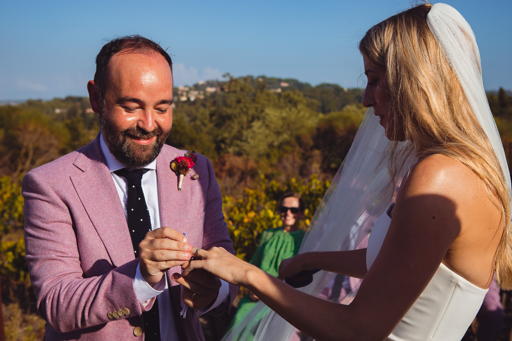The groom puts a ring on the bride's finger during the wedding ceremony at their destination wedding in Corfu
