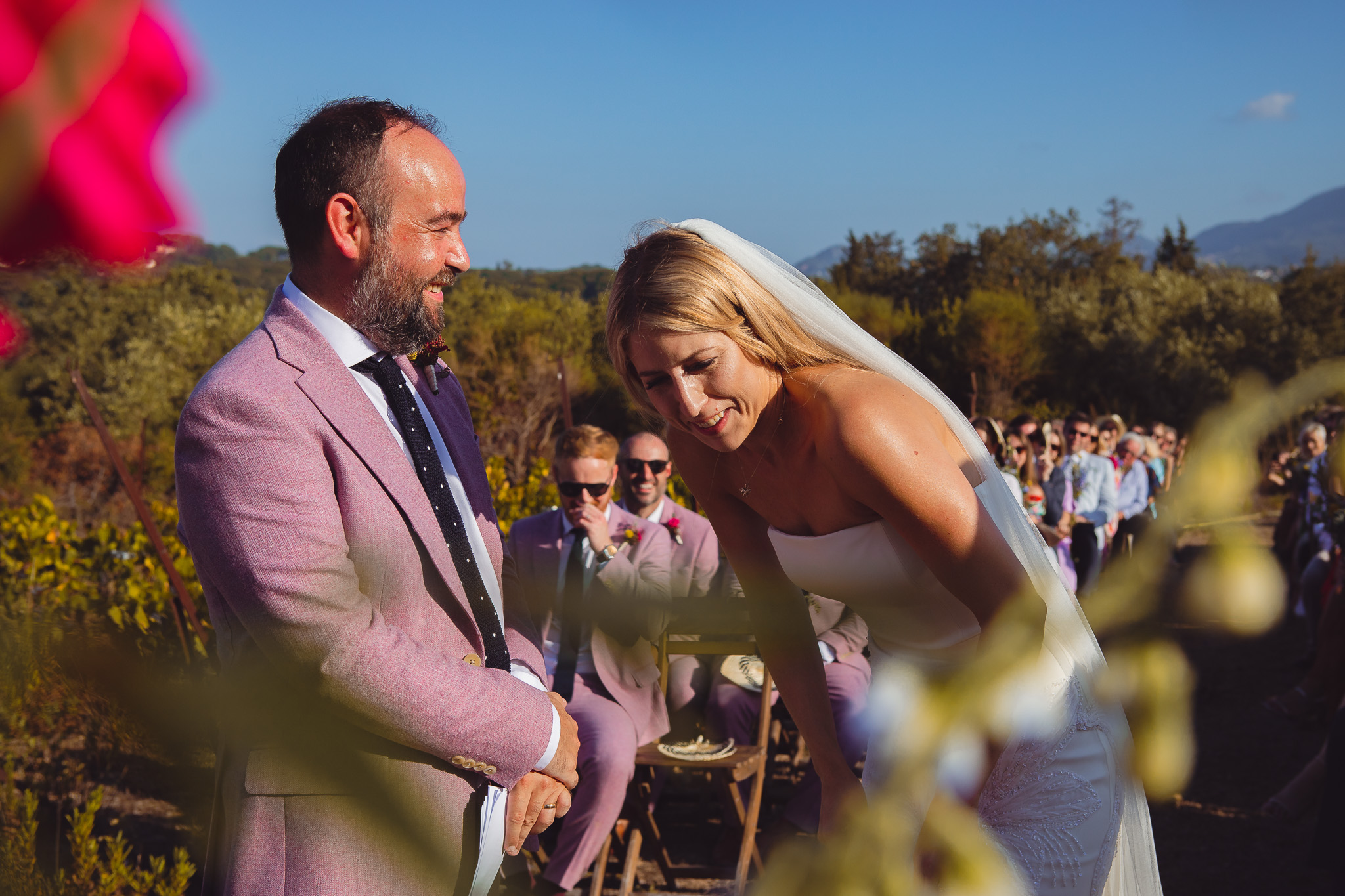 The bride laughs with the groom during their wedding ceremony at Ambelonas Vineyard, Corfu